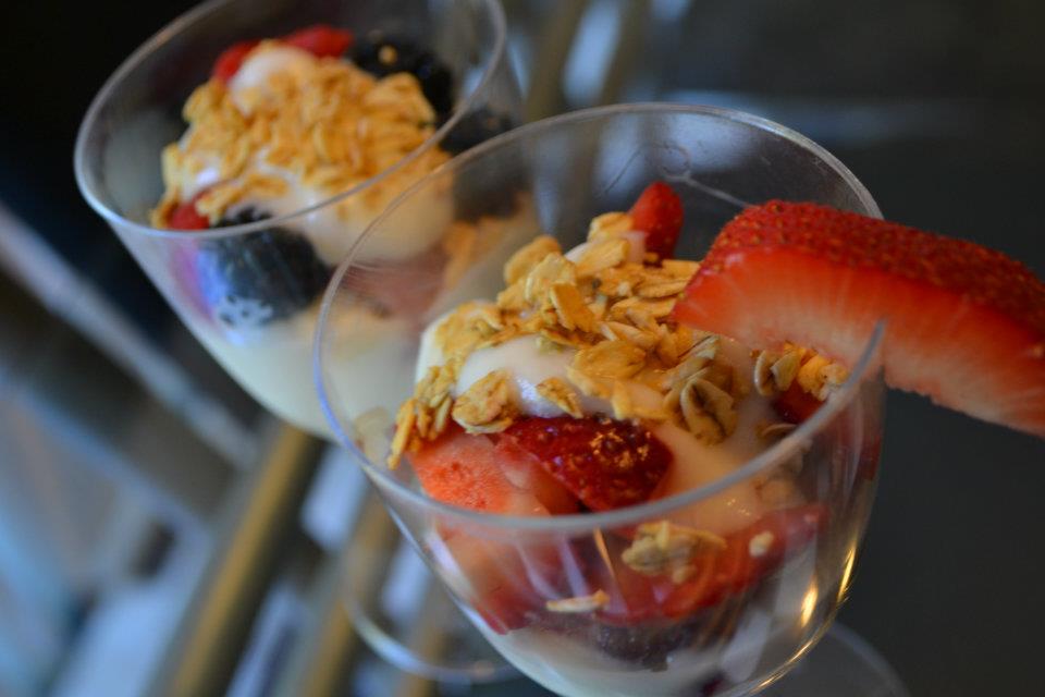 Two clear cups of fruit and yogurt parfaits topped with granola.