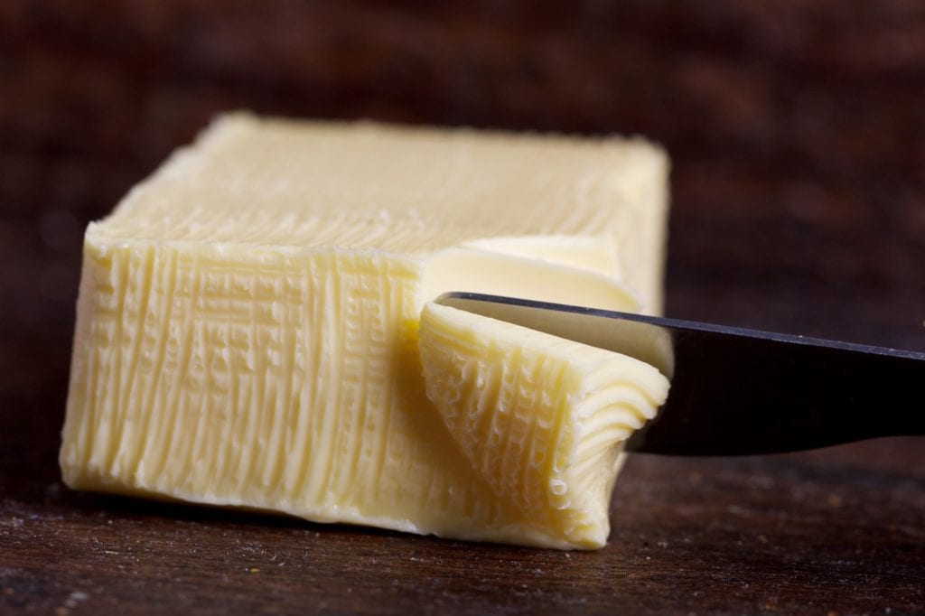 Slab of butter with butter knife cutting through it