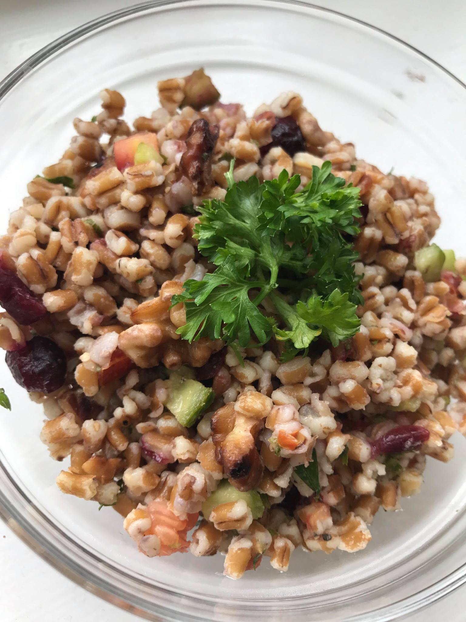 A bowl of wheat berry salad garnished with parsley