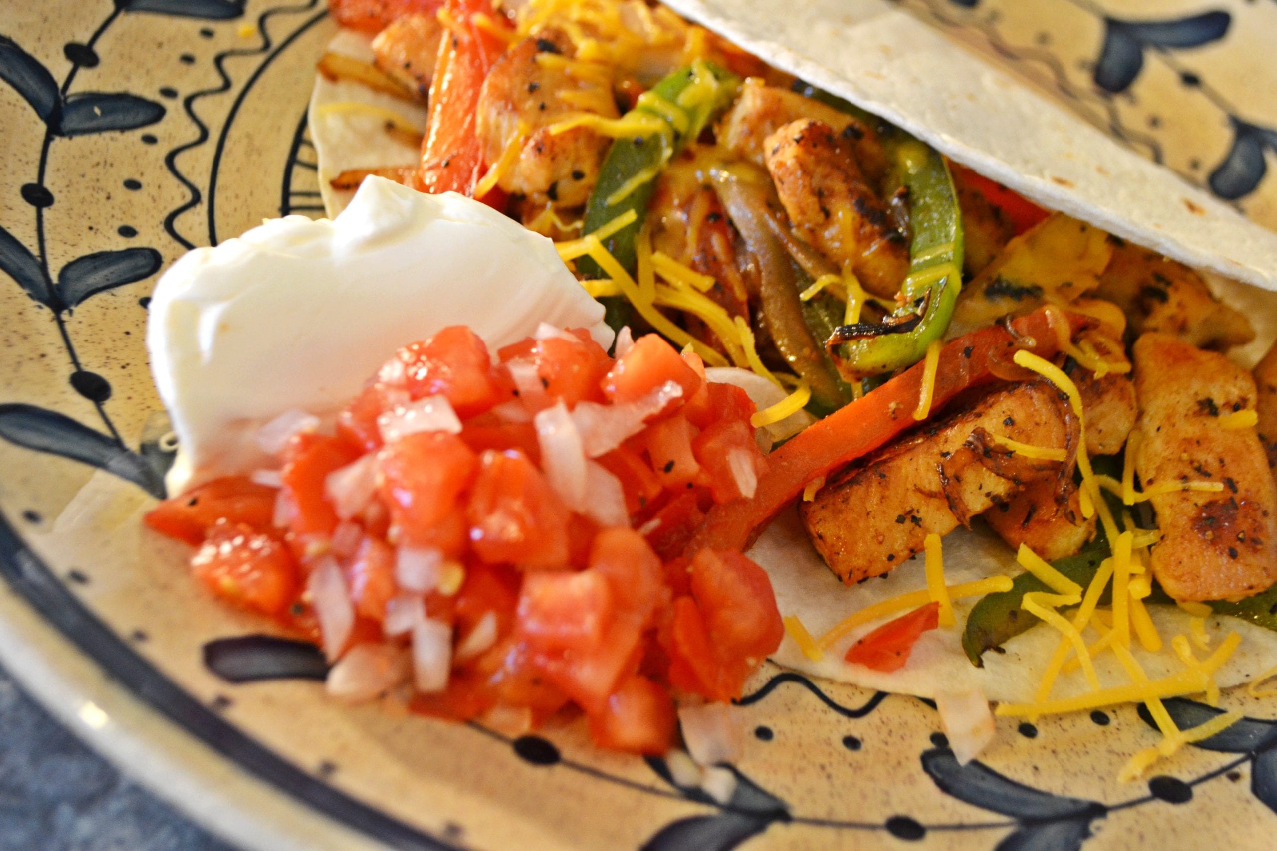Fajita on a plate with a side of sour cream and salsa
