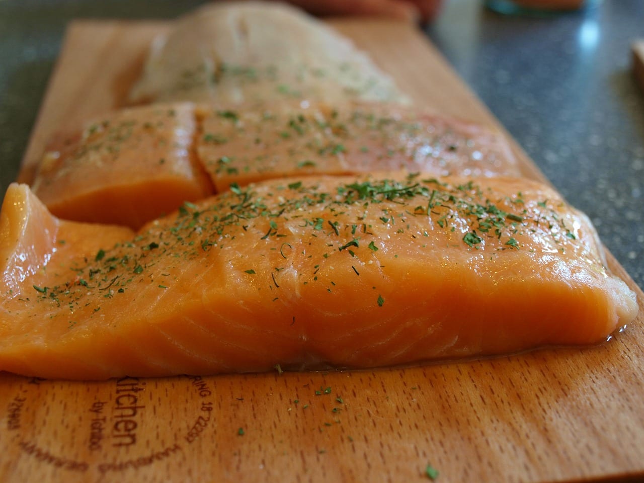 Raw seasoned salmon fillets on wooden cutting board