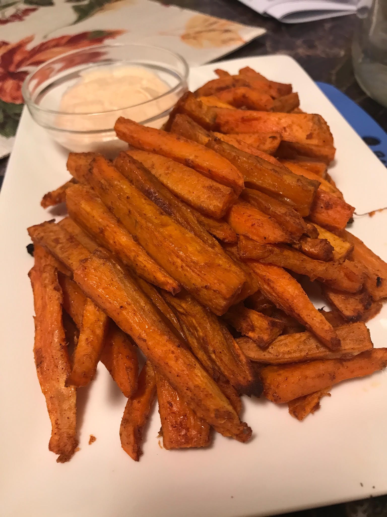Sweet potato fries layered on a white rectangular serving plate with dipping sauce.