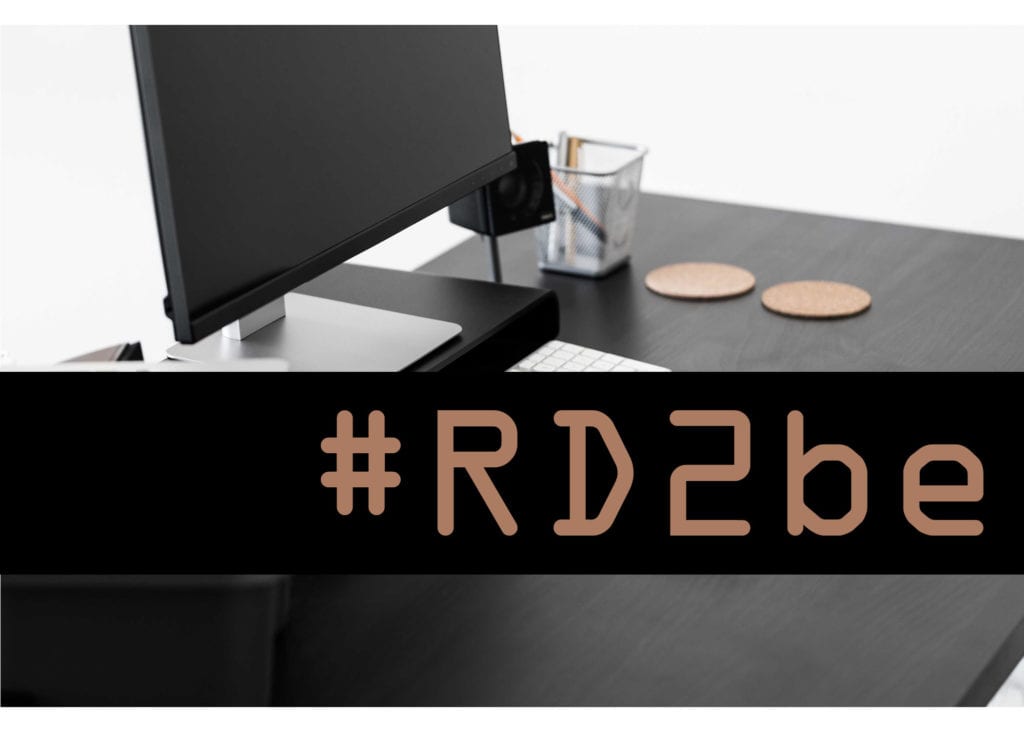 Minimalist desk with the text "#RD2be"